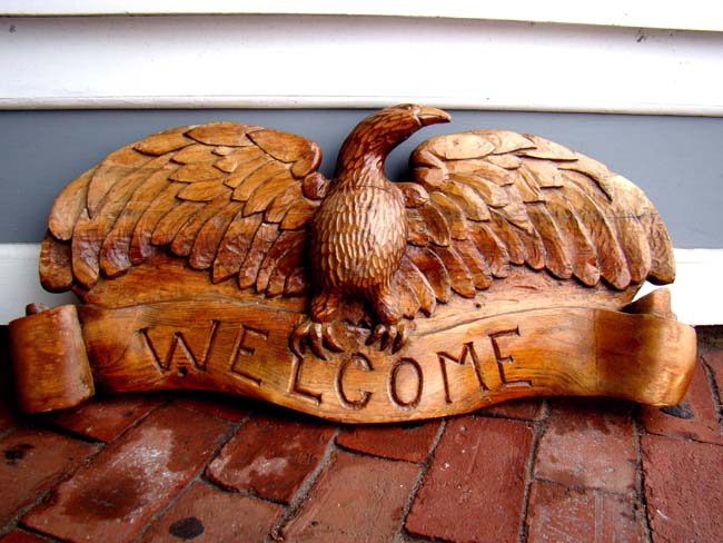 A carved eagle plaque with the inscription "WELCOME" circa 1900-1920